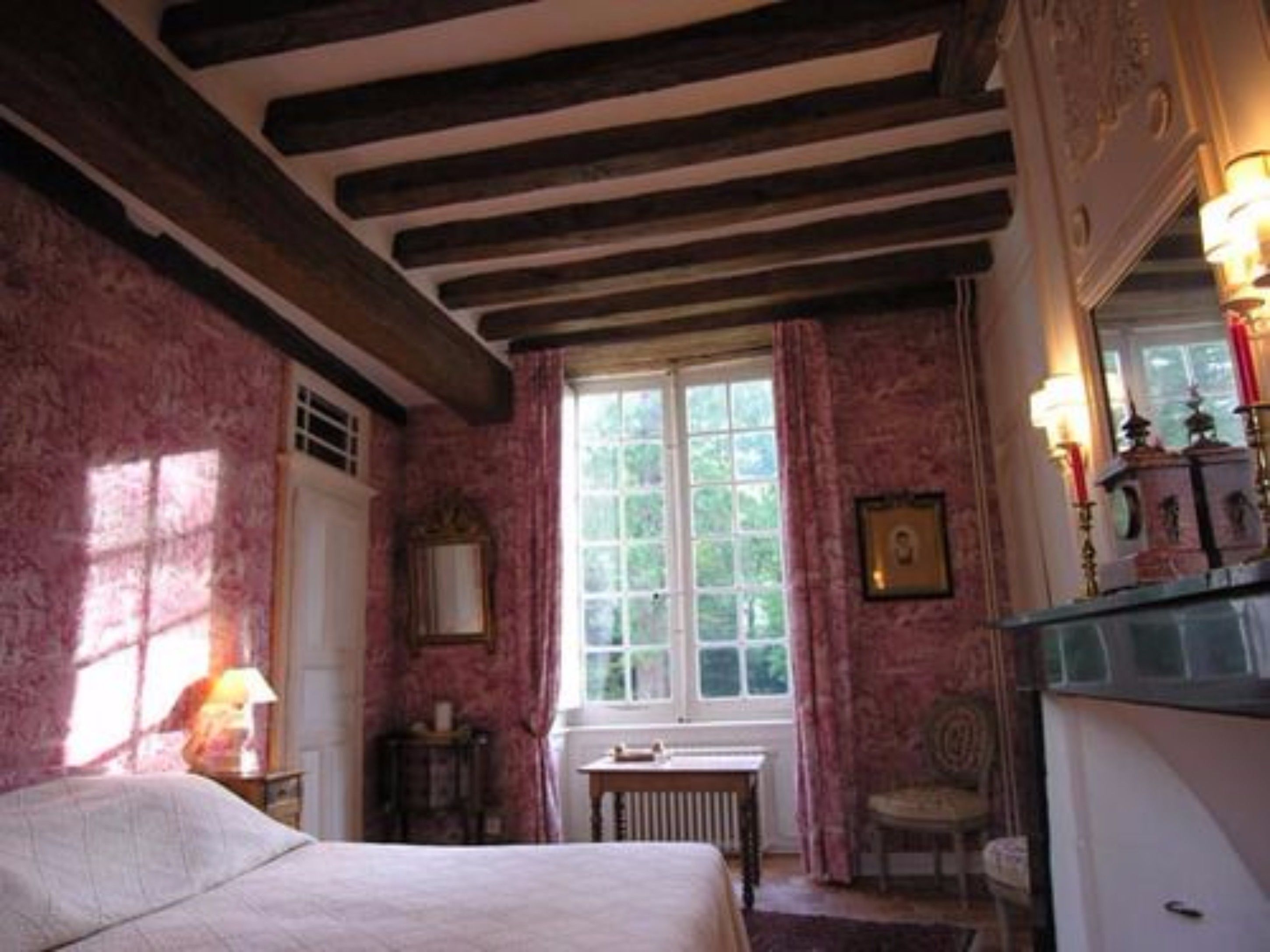A room with a bed, a window, a table, and a chair.