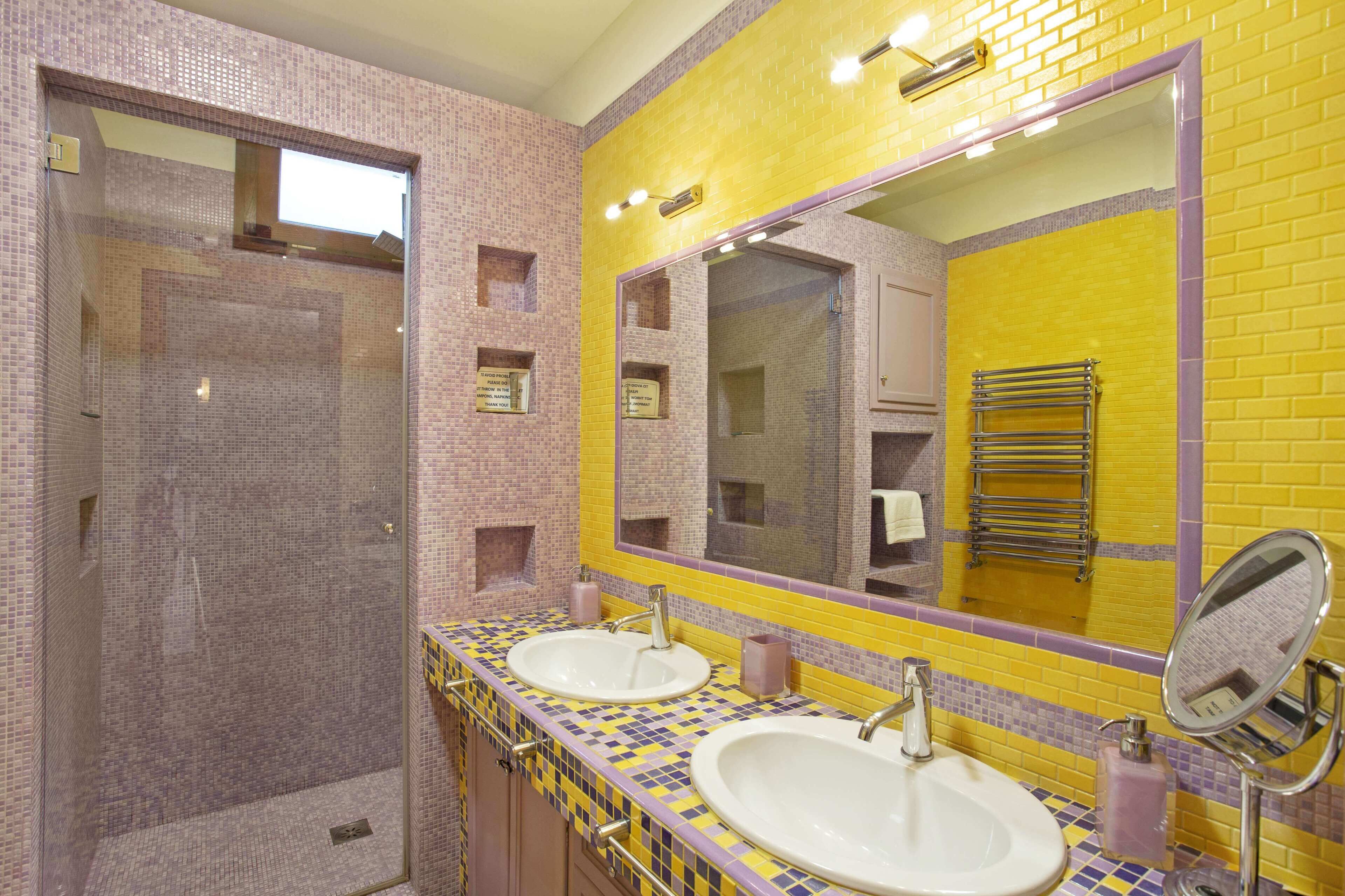 A bathroom with two sinks, a large mirror, and a shower area.