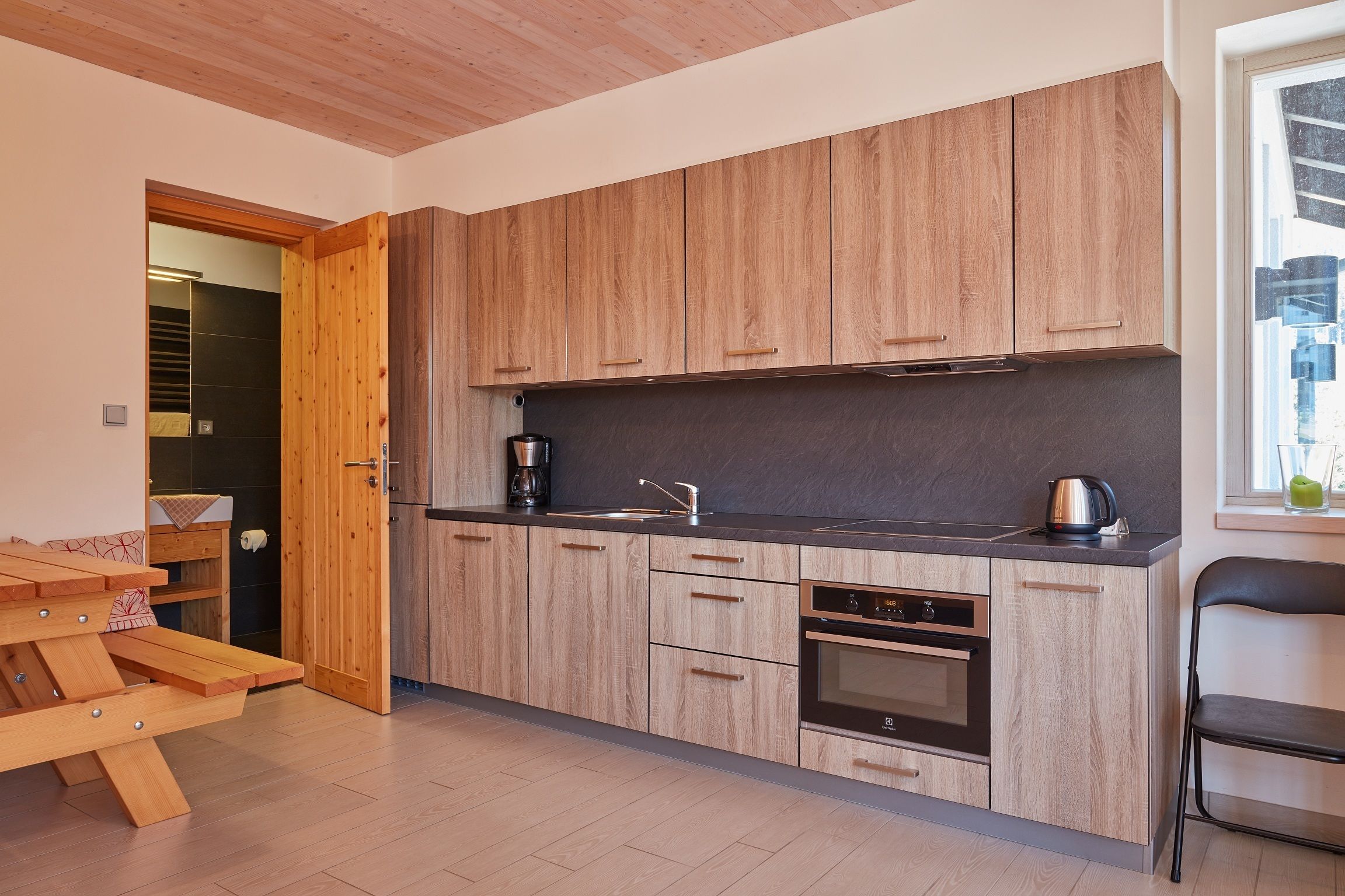 A modern kitchen with wooden cabinets, a black countertop, and a built-in oven.