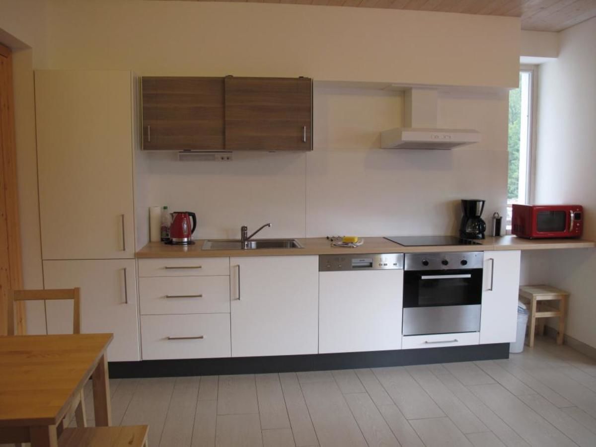 A modern kitchen with white cabinets, a stainless steel oven, and a microwave.