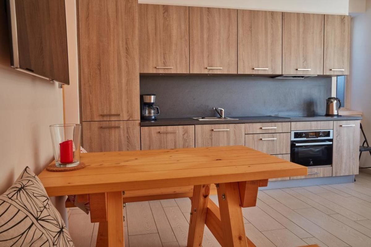 Une cuisine moderne avec des meubles en bois, un plan de travail noir et un four encastré.
