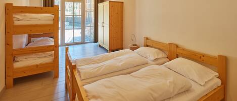 Una habitación con dos camas literas de madera, un armario de madera y una pequeña mesa.