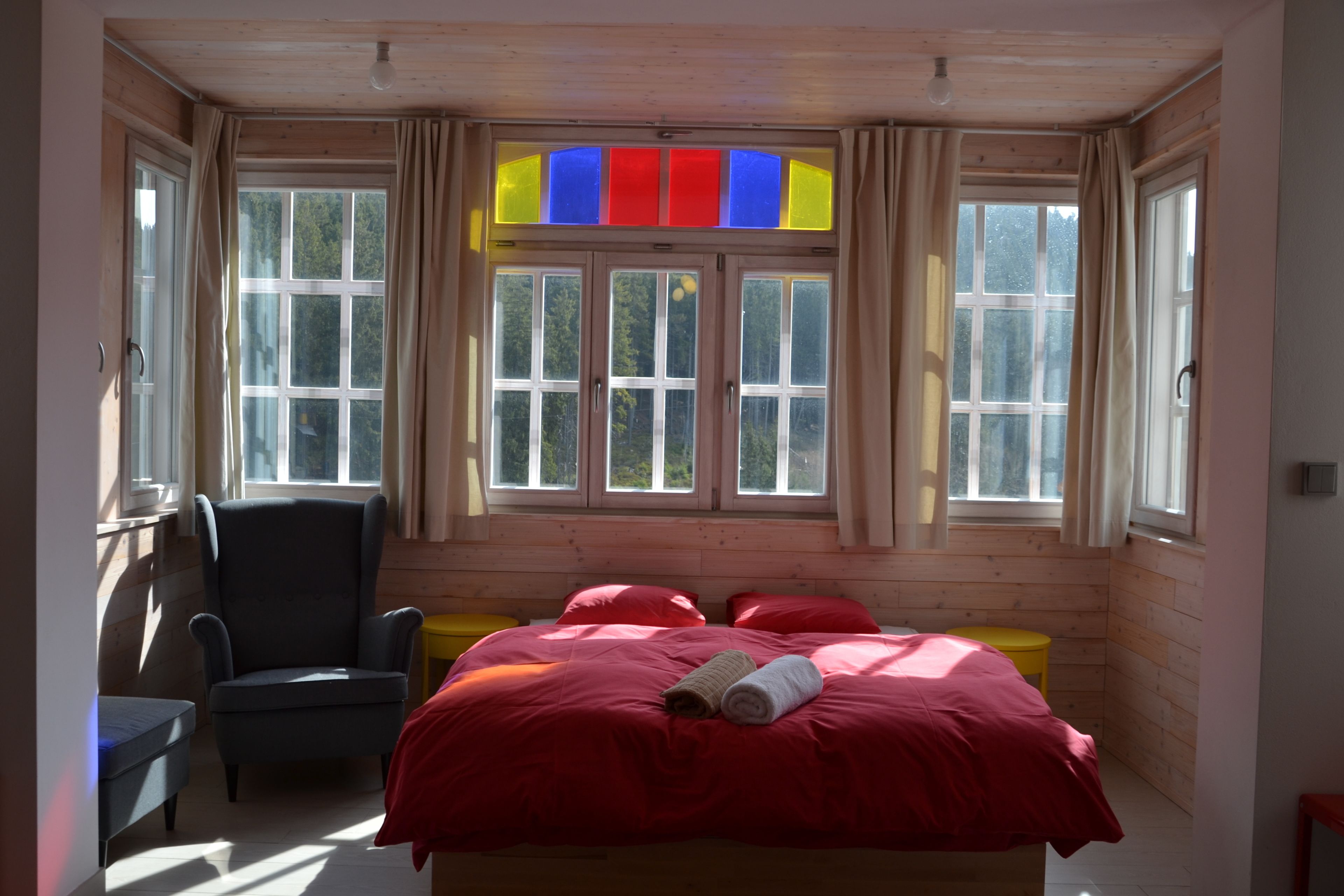A room with a bed, a chair, and a window with curtains.