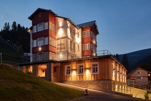 A multi-story building with a wooden facade and stone accents, featuring a sign that reads "SNEZKA." - Residence Sněžka (Pec pod Snezkou)