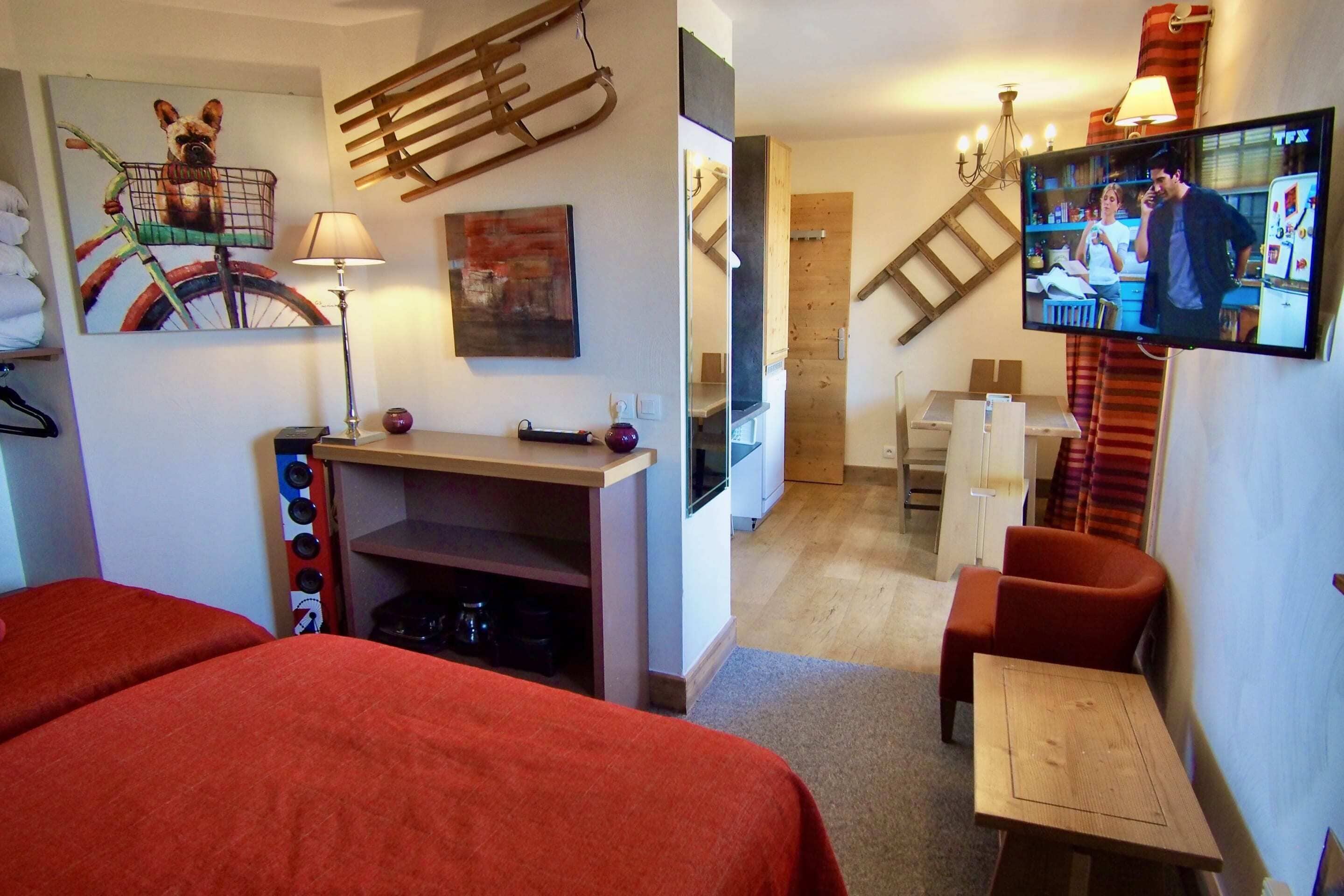 Una habitación de hotel con una cama, un escritorio, un televisor y un estante en la pared.