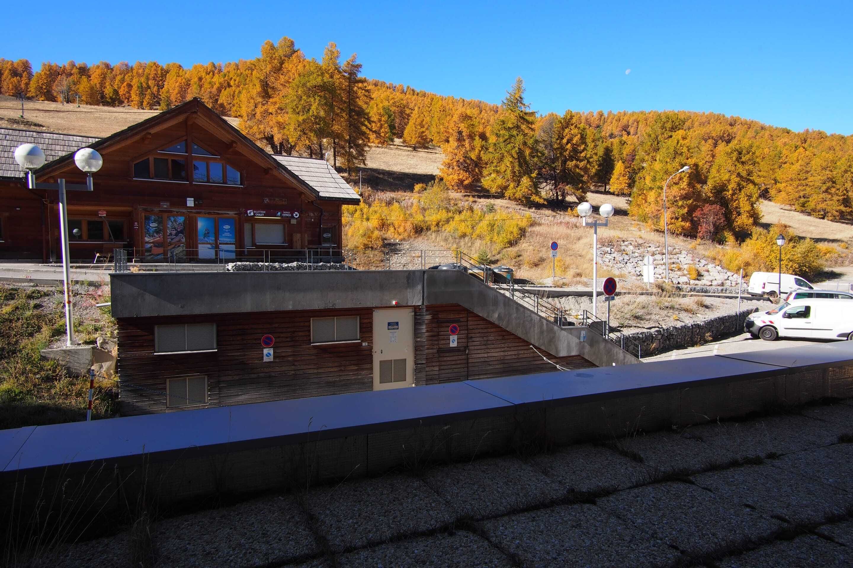 Un chalet en bois doté d’un balcon donnant sur une colline boisée.