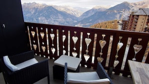A balcony with wicker furniture and heart-shaped decorations, overlooking a mountainous landscape. - RisoulSki Antarès (Risoul)