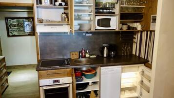 A compact kitchen with a microwave, sink, and built-in oven.