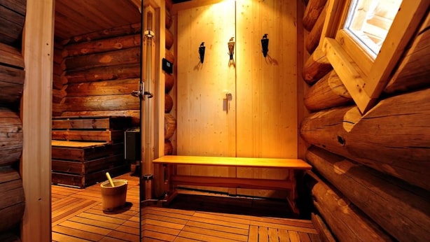 A sauna with wooden walls, a bench, and a bucket. - RisoulSki Antarès (Risoul)