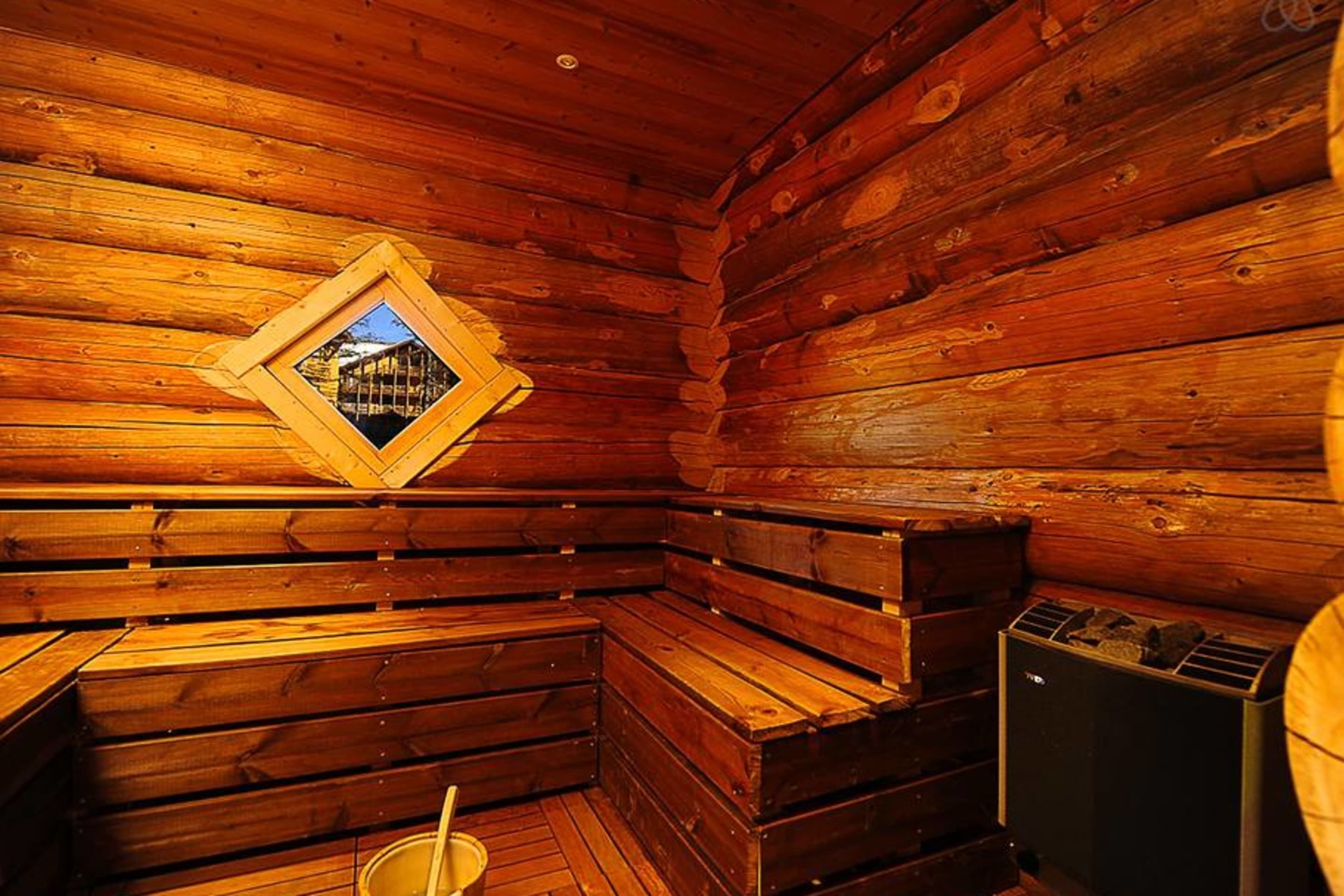 L’intérieur d’une cabane en rondins, avec un banc en bois, une petite fenêtre et un radiateur.