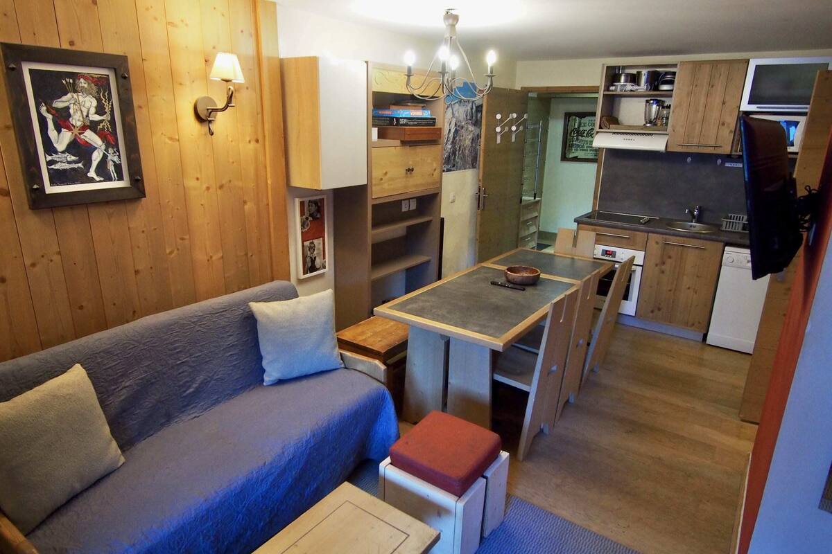 A compact living space with a sofa, a small table, a kitchenette, and a dining area.