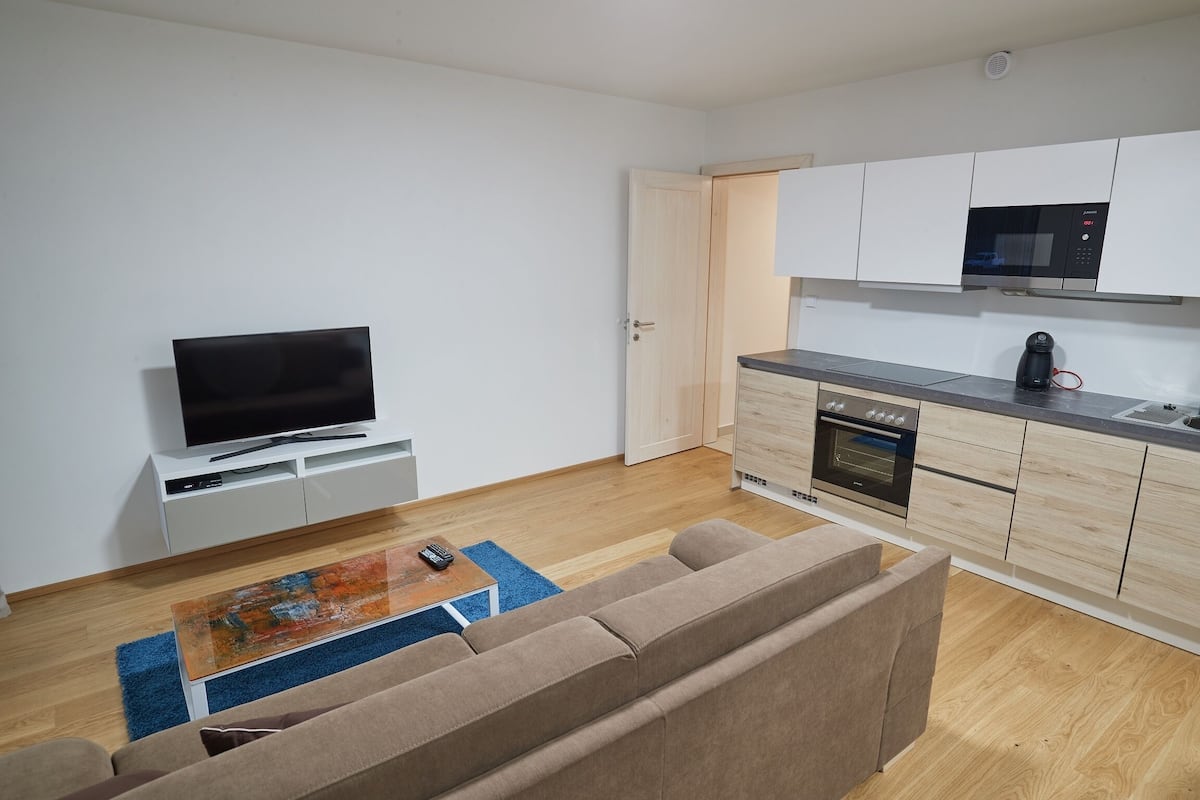 A modern living room with a flat-screen TV, a sofa, and a coffee table.