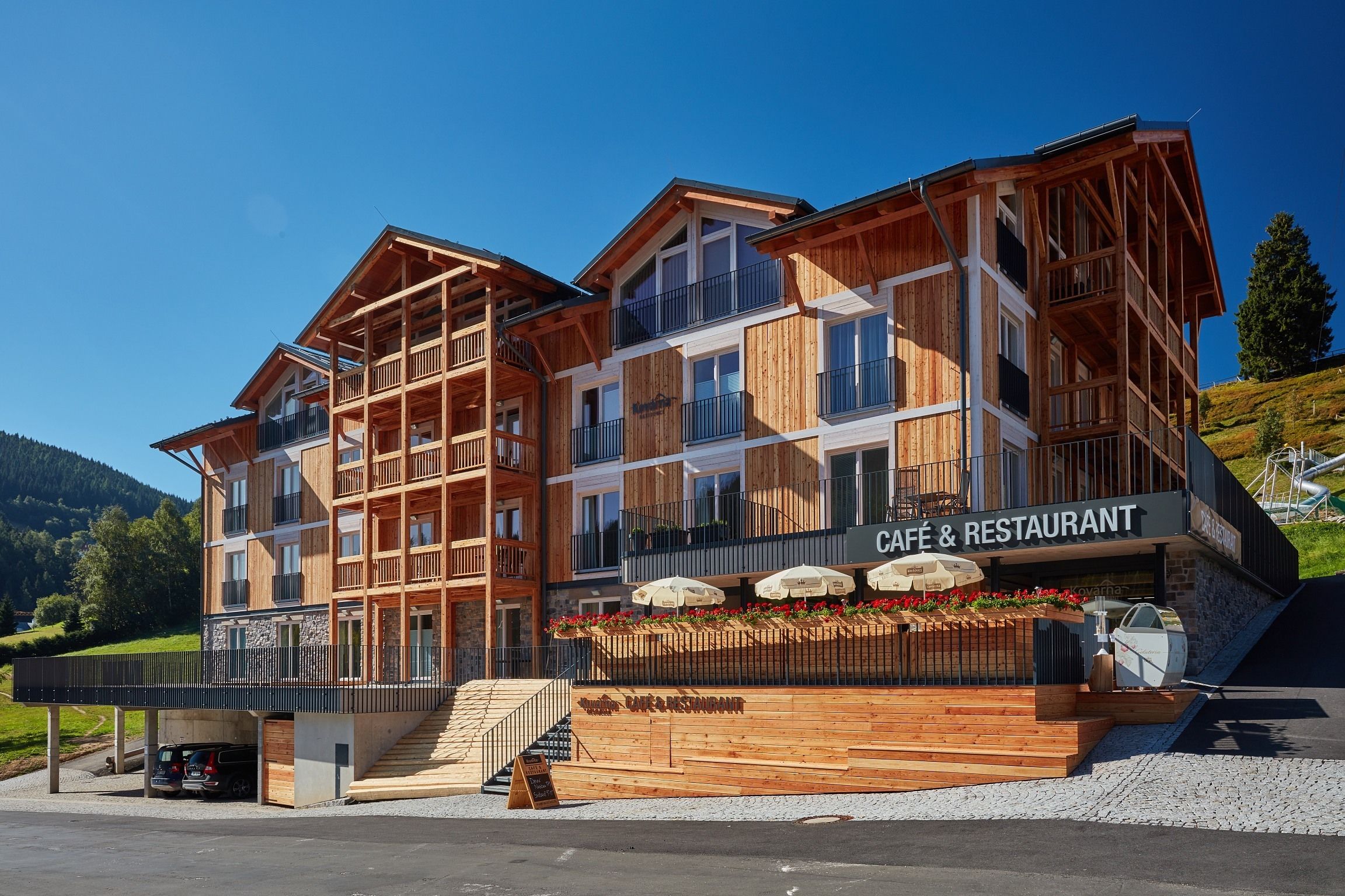 A multi-story wooden building with balconies and a cafe & restaurant sign.