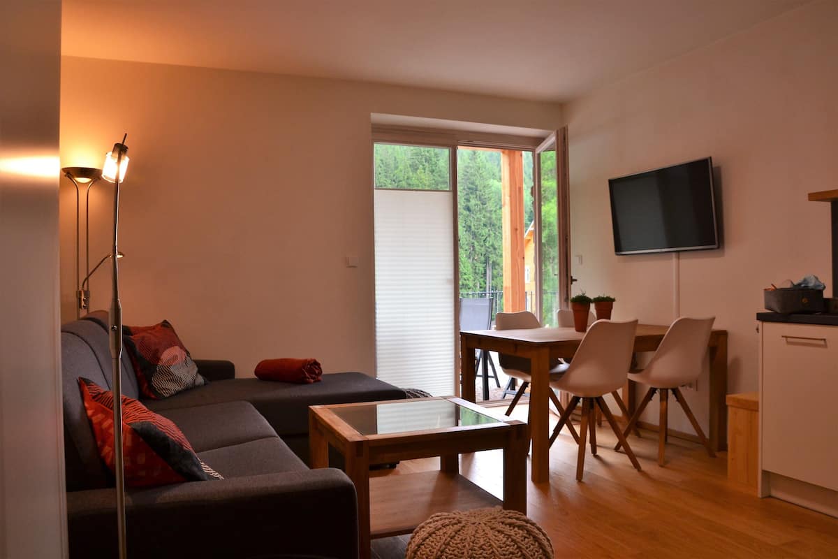 A modern living room with a sofa, a coffee table, and a dining area with chairs and a table.