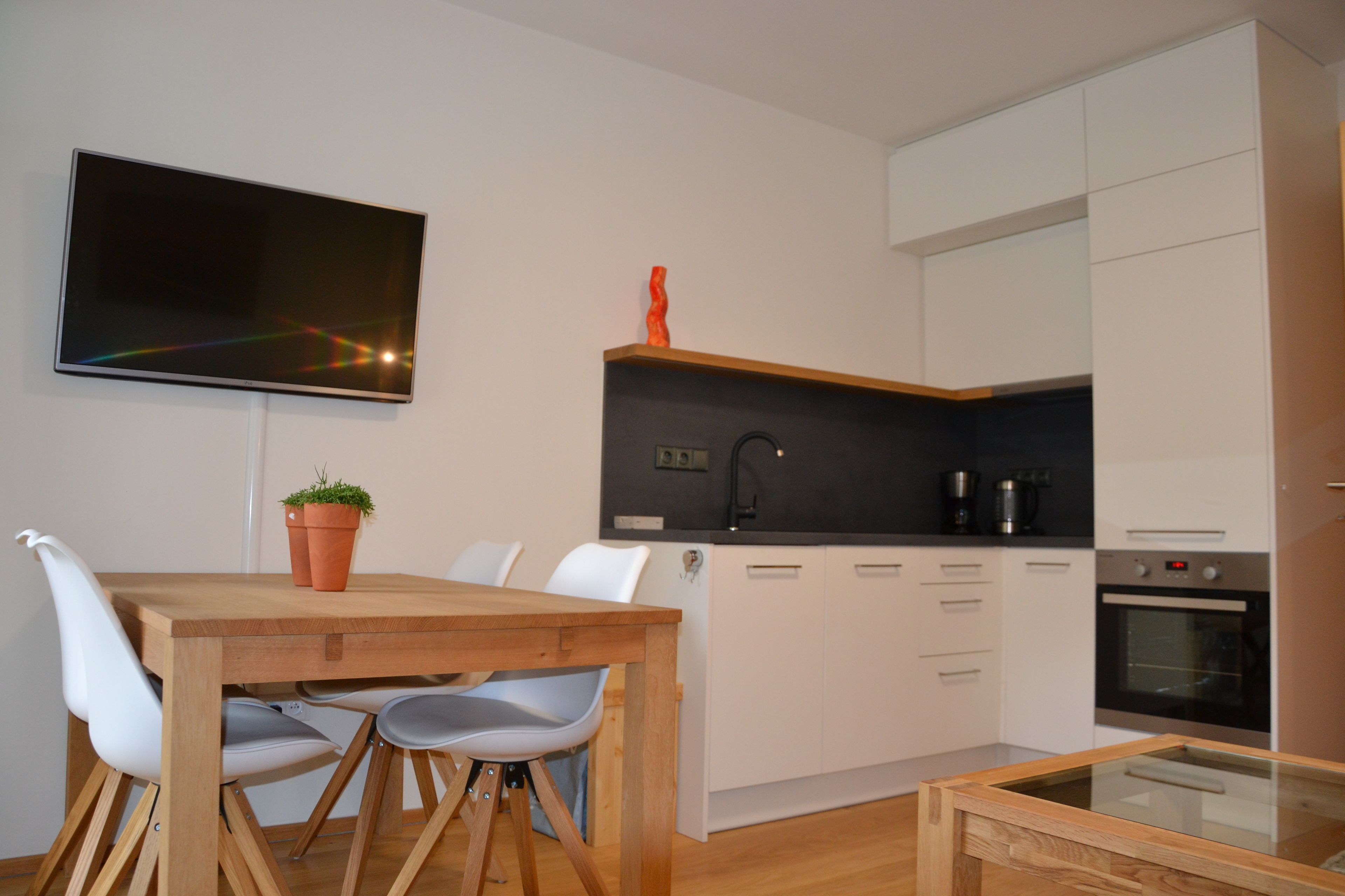 A modern kitchen with white cabinets, a black countertop, and a built-in oven.