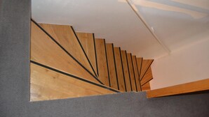 A wooden staircase with a modern design, leading to a ceiling with a geometric pattern. - Apartments Holiday Pec (Pec pod Snezkou)