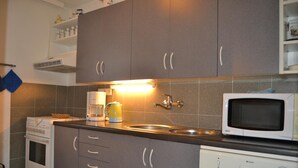 A kitchen with grey cabinets, a white dishwasher, a white microwave, and a coffee maker. - Apartments Holiday Pec (Pec pod Snezkou)
