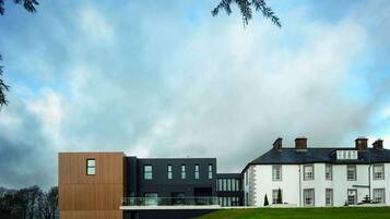 A modern building with a mix of wooden and dark-colored panels, large windows, and a well-maintained lawn.