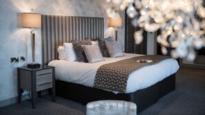 A modern bedroom with a large bed, two bedside tables, and a decorative chandelier.