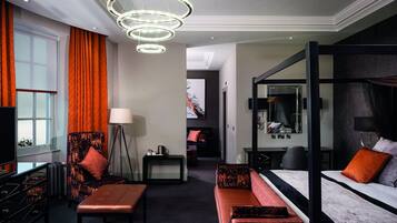 Quarto de hotel moderno com uma cama grande, um sofá, uma escrivaninha e um espelho amplo.
