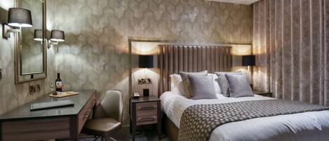 A hotel room with a bed, desk, chair, and nightstand.