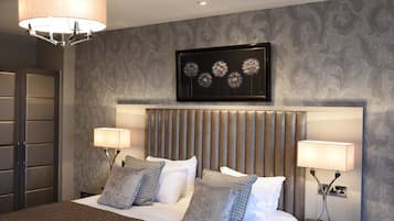 Ein modernes Hotelzimmer mit einem großen Bett, zwei Nachttischen, einem Bettkopfteil mit vertikalen Lamellen und einem gerahmten Kunstwerk darüber.