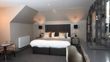 A modern hotel room with a large bed, two bedside tables with lamps, a small desk, and a chair.