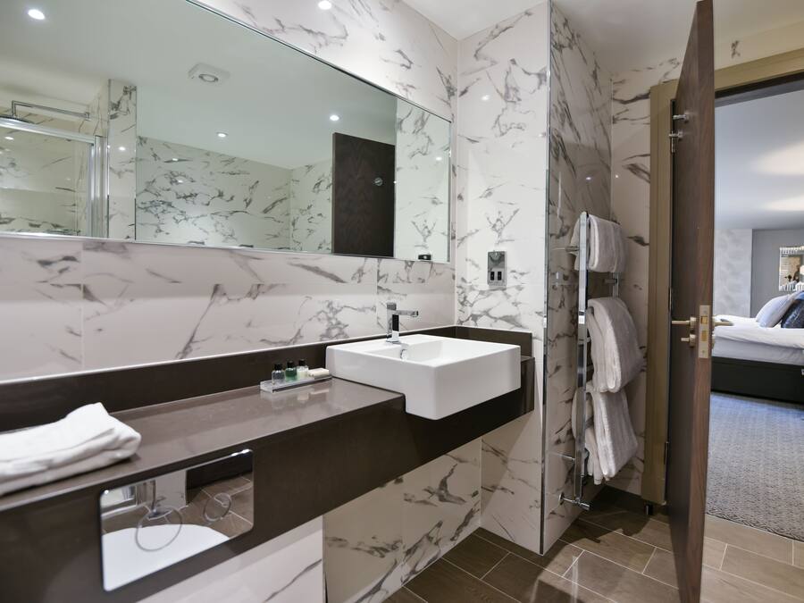 A modern bathroom with a marble vanity, a large mirror, and a shower area.