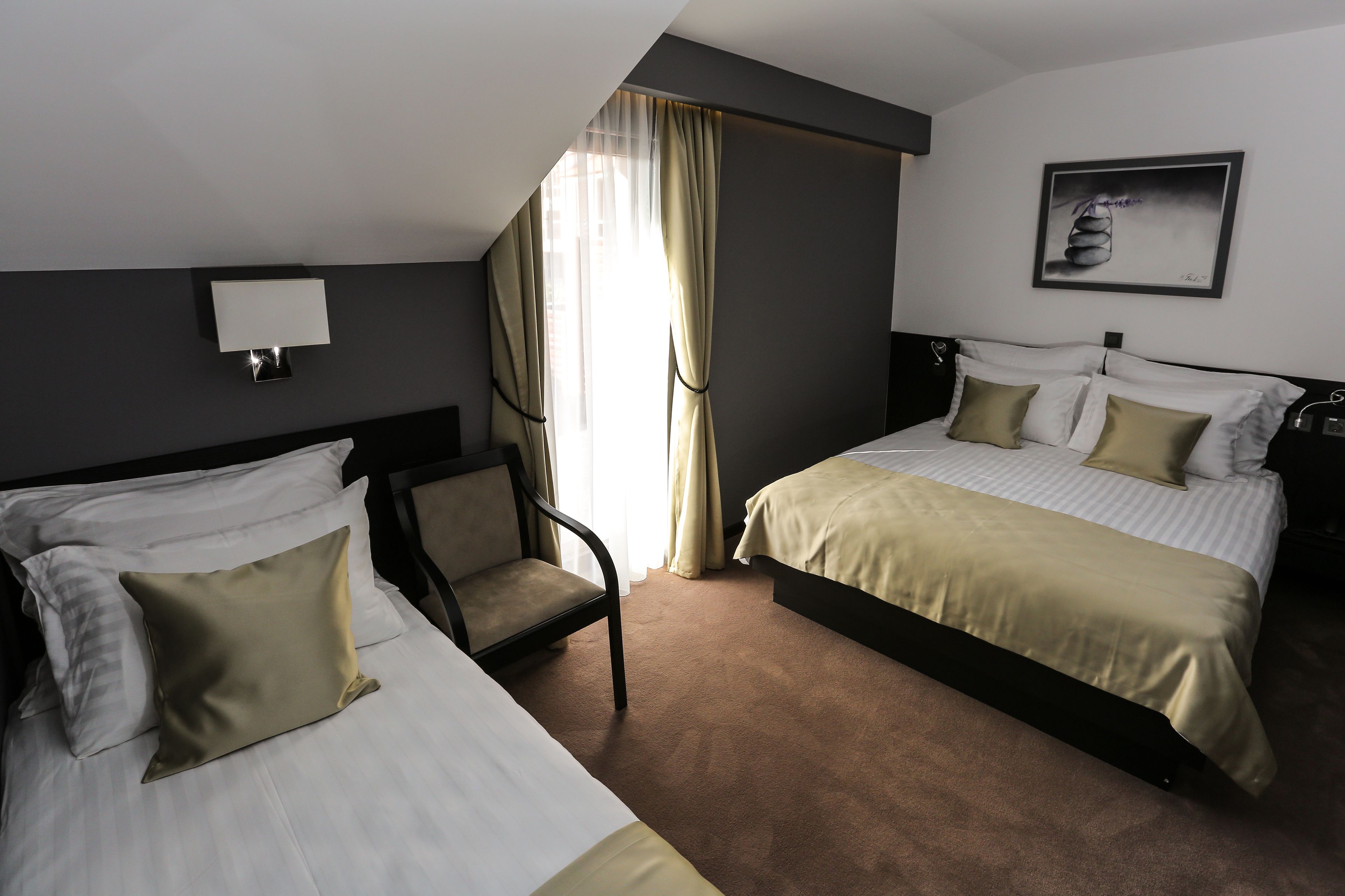 Een hotelkamer met twee bedden, een stoel, een lamp en een schilderij aan de muur.