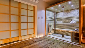 Una habitación tradicional japonesa con suelo de tatami, una puerta corredera de vidrio que da a un lavabo y un toallero visible.