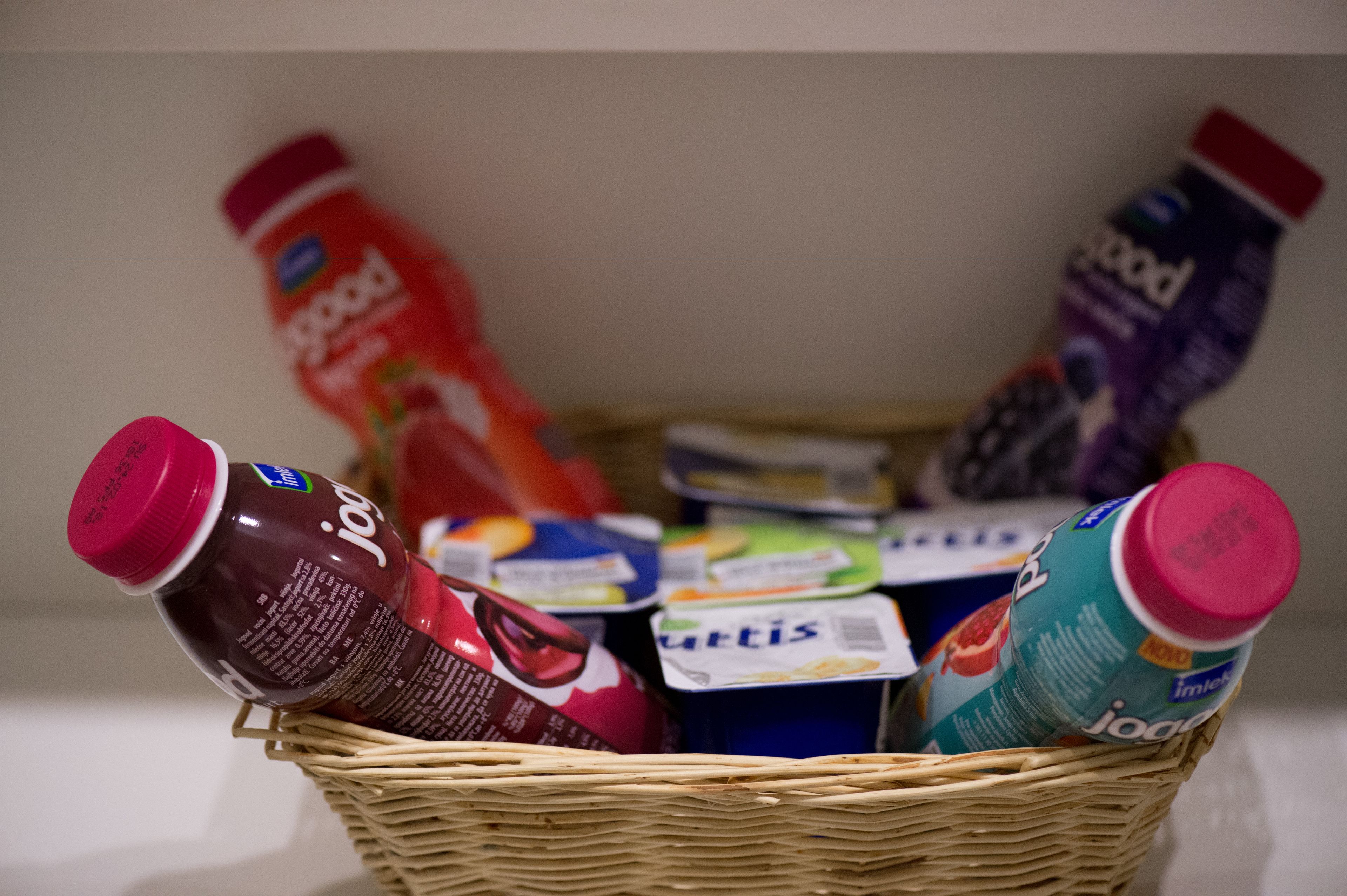 A wicker basket containing various food items including jars of jam and a carton of juice.