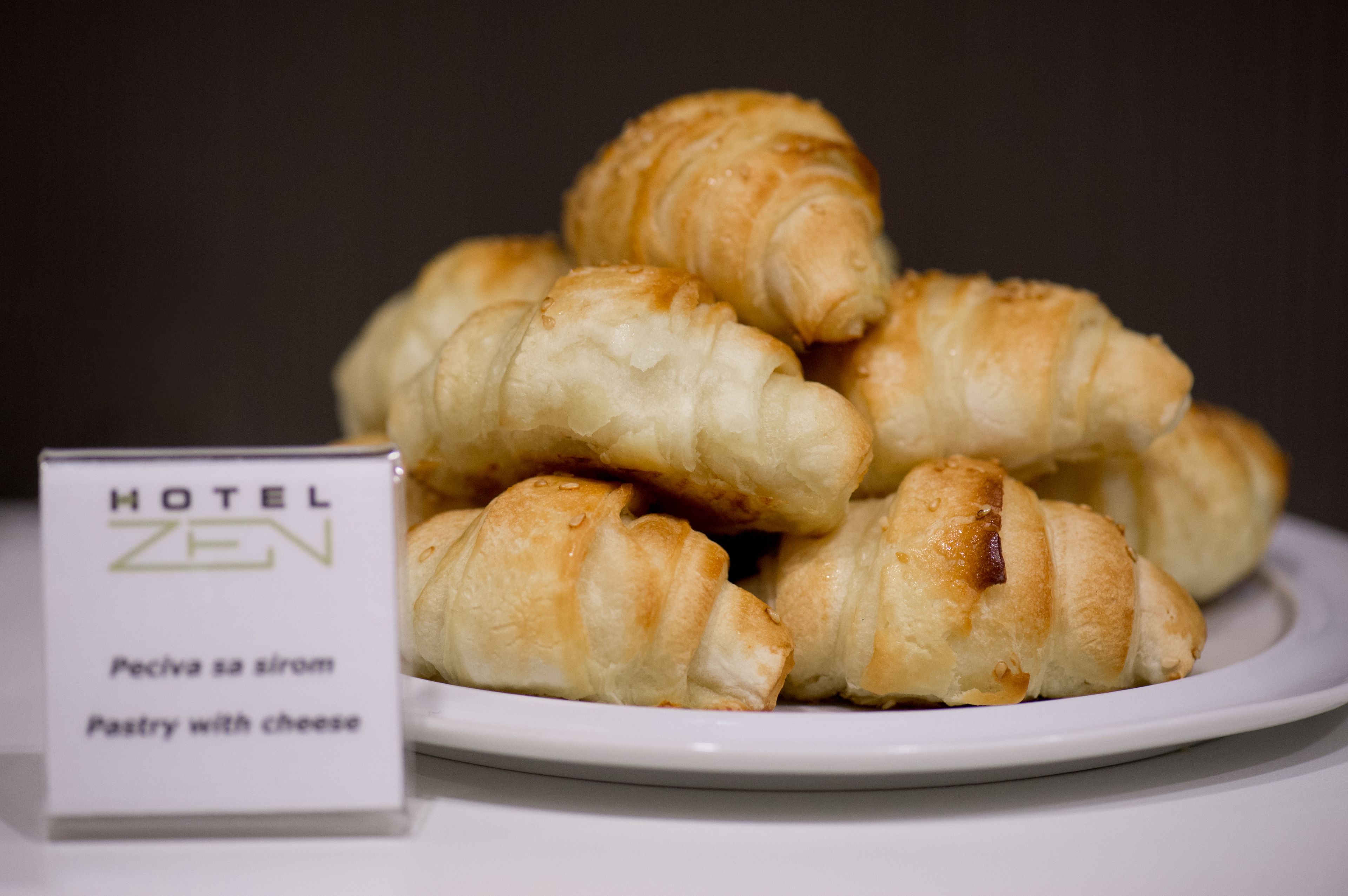 Ein Teller mit Croissants und ein Schild mit der Aufschrift 'HOTEL ZEN Gebäck mit Käse'.