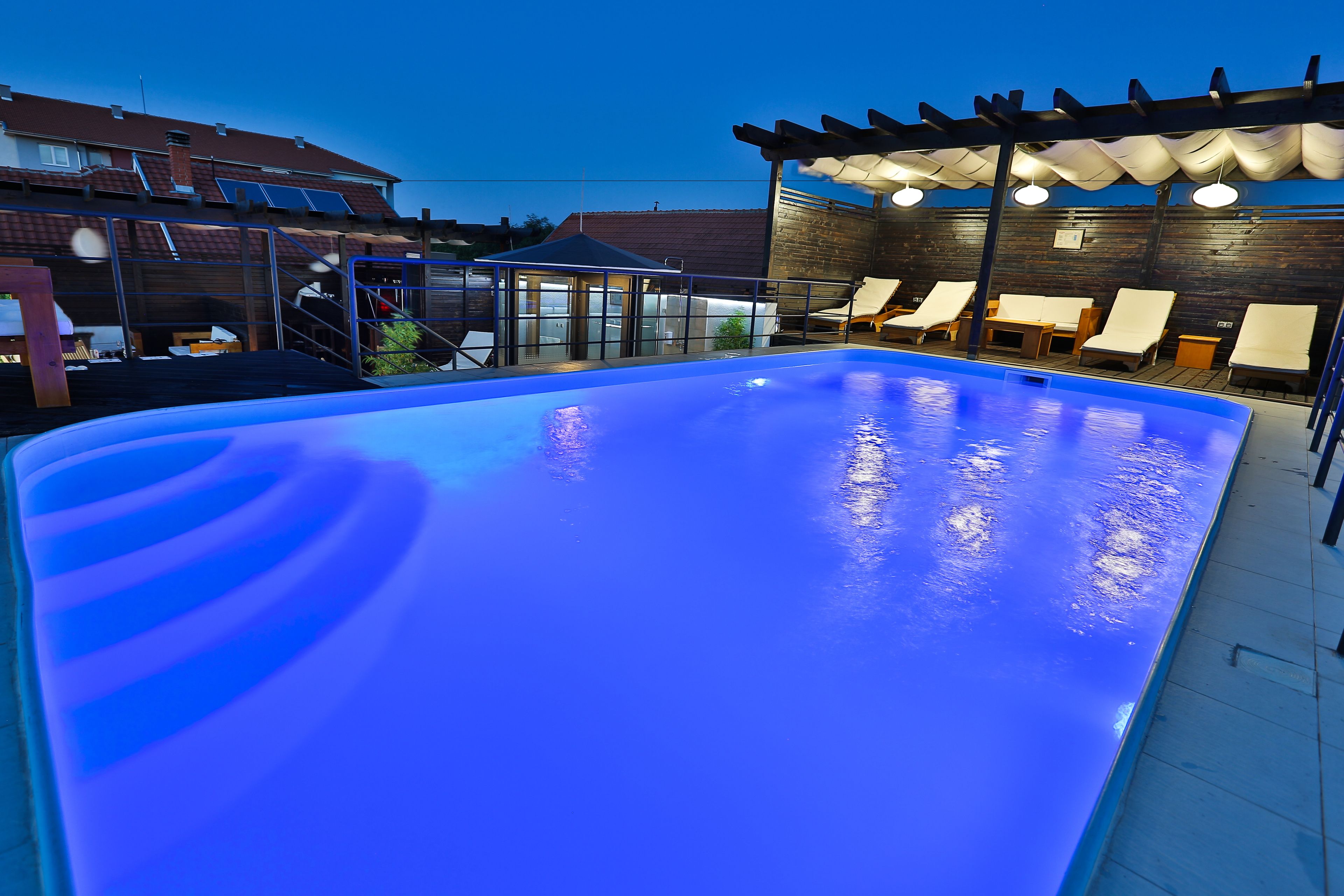 A swimming pool with a pergola and lounge chairs.