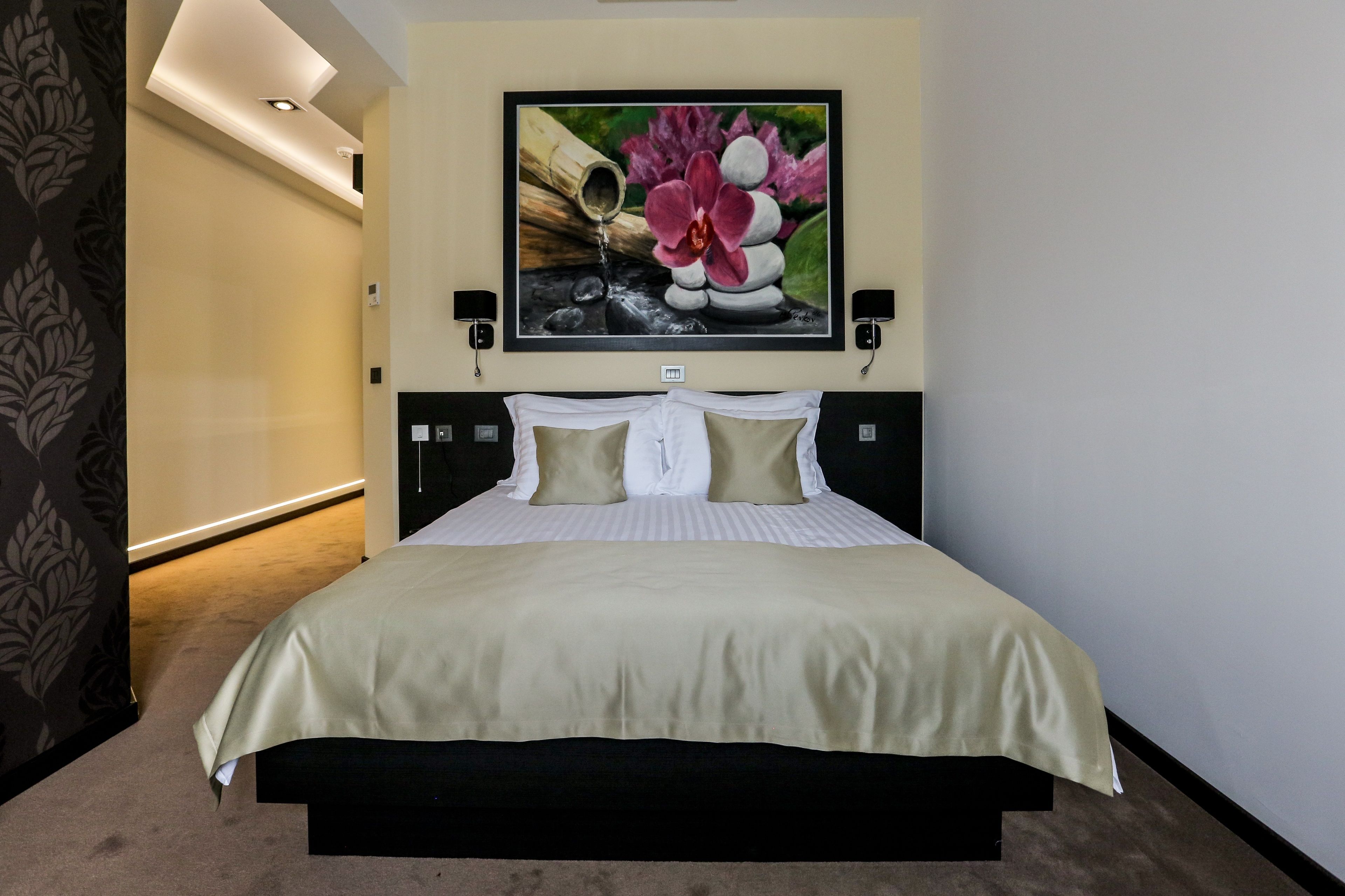 Une chambre d’hôtel avec un lit, un tableau accroché au mur et une table de chevet avec une lampe.