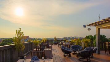 A terrace with tables and chairs, a pergola, and a view of the cityscape.
