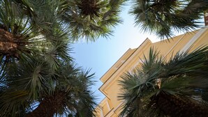 A view of a building with a yellow facade and palm trees in the foreground. - Villa Paganini B&B (Rome)
