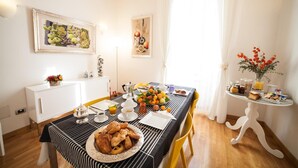 A dining area with a striped tablecloth, a fruit bowl, and a plate of pastries. - Villa Paganini B&B (Rome)