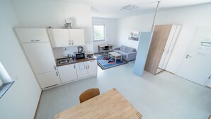 Un appartement compact et moderne comprenant une kitchenette, un coin repas, un canapé et un petit espace bureau.