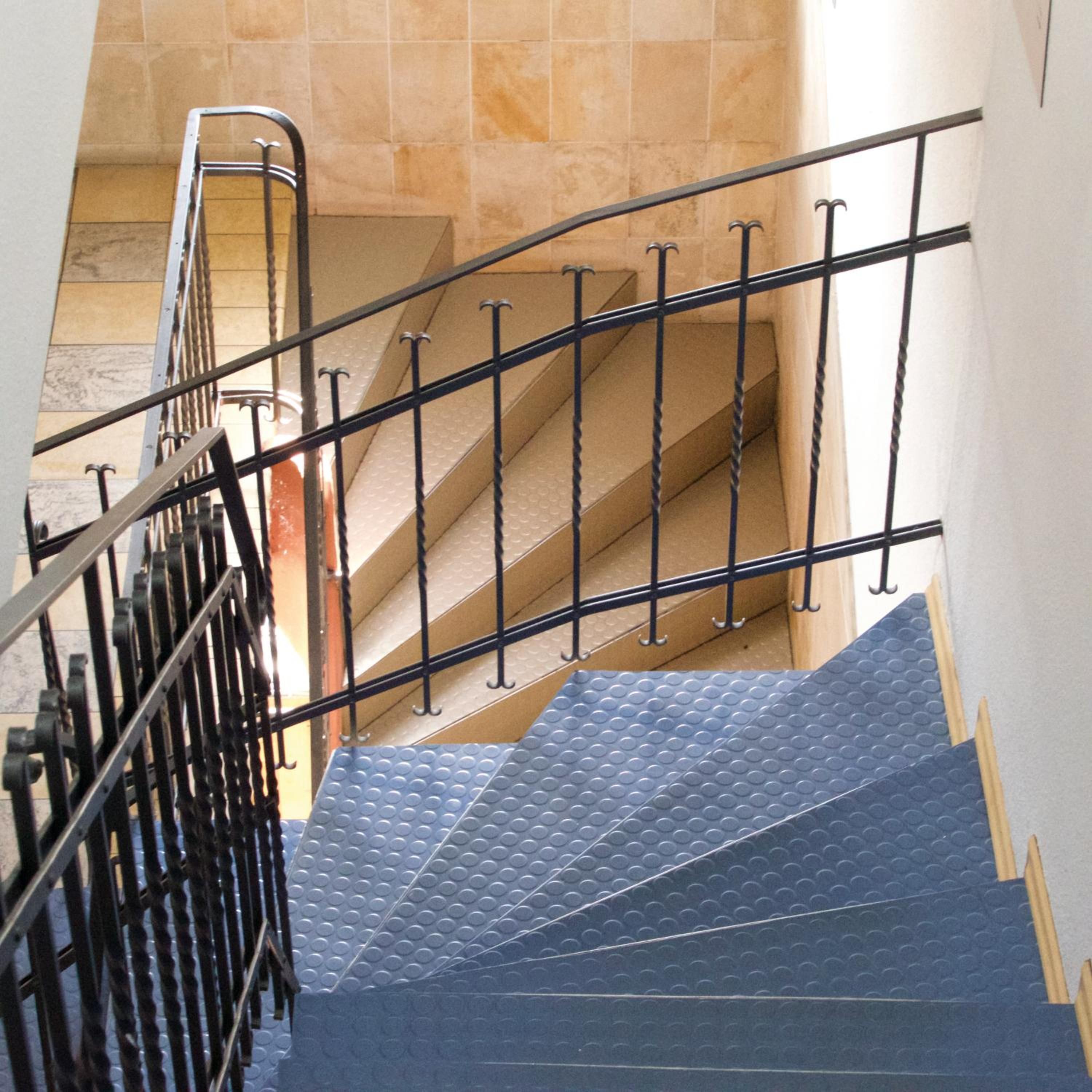 A staircase with metal railings and a textured blue carpet.
