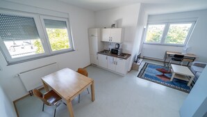 Une cuisine compacte avec un coin repas, une petite table et une chaise. On y trouve des placards, un four à micro-ondes et une bouilloire.