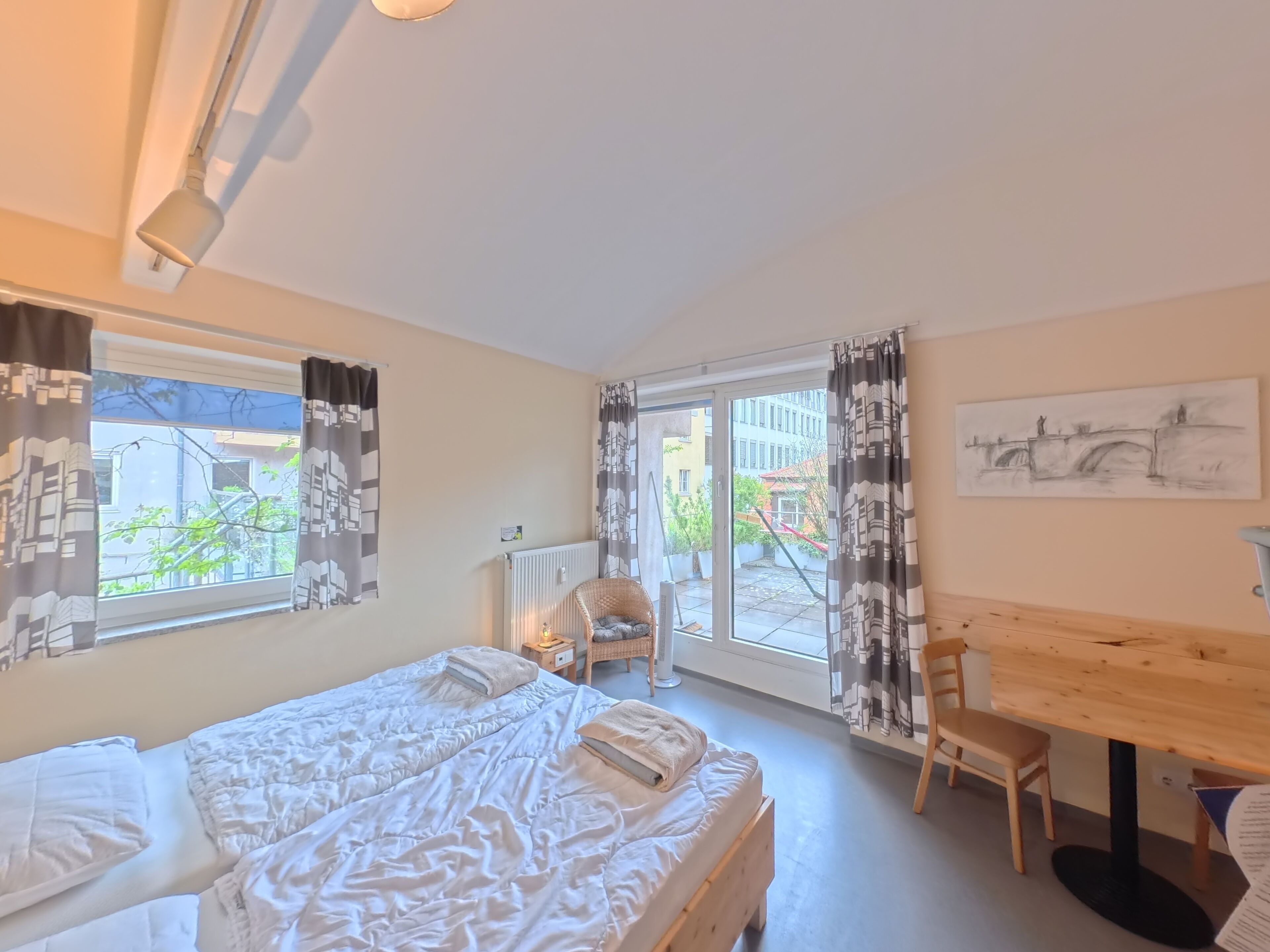 Un dormitorio con cama, una silla, una mesa y vistas al exterior.