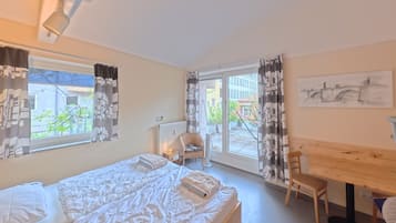 Un dormitorio con cama, una silla, una mesa y vistas al exterior.