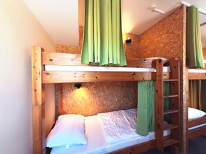 A bunk bed with a ladder, a pillow, and a green curtain. - Babelfish Hostel (Würzburg)