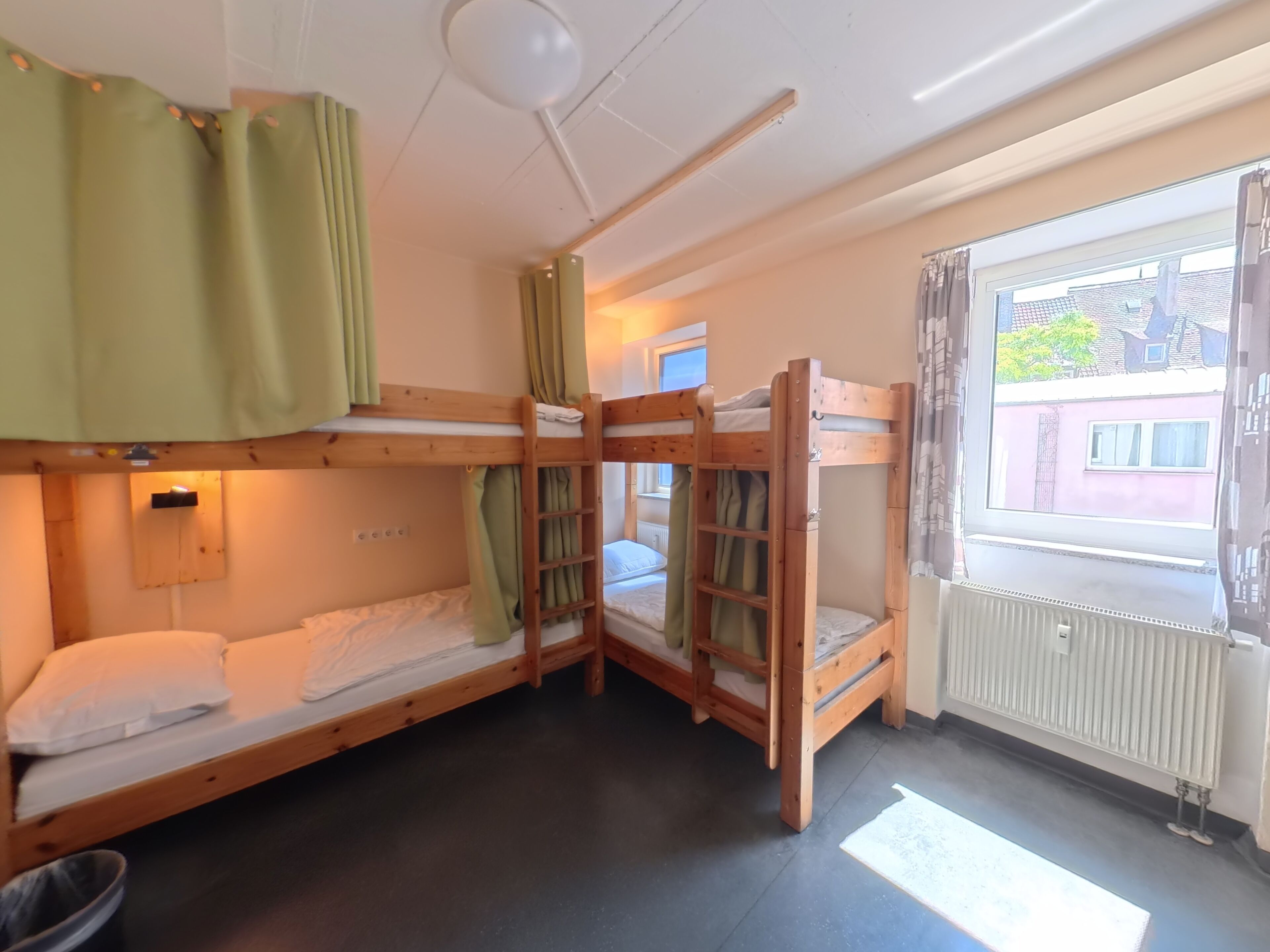 Una habitación con literas, un radiador y una ventana con cortinas.