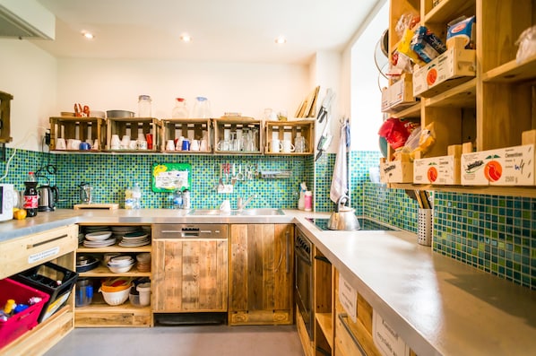 Una cocina con armarios de madera, salpicadero de azulejos y diversos utensilios y electrodomésticos.
