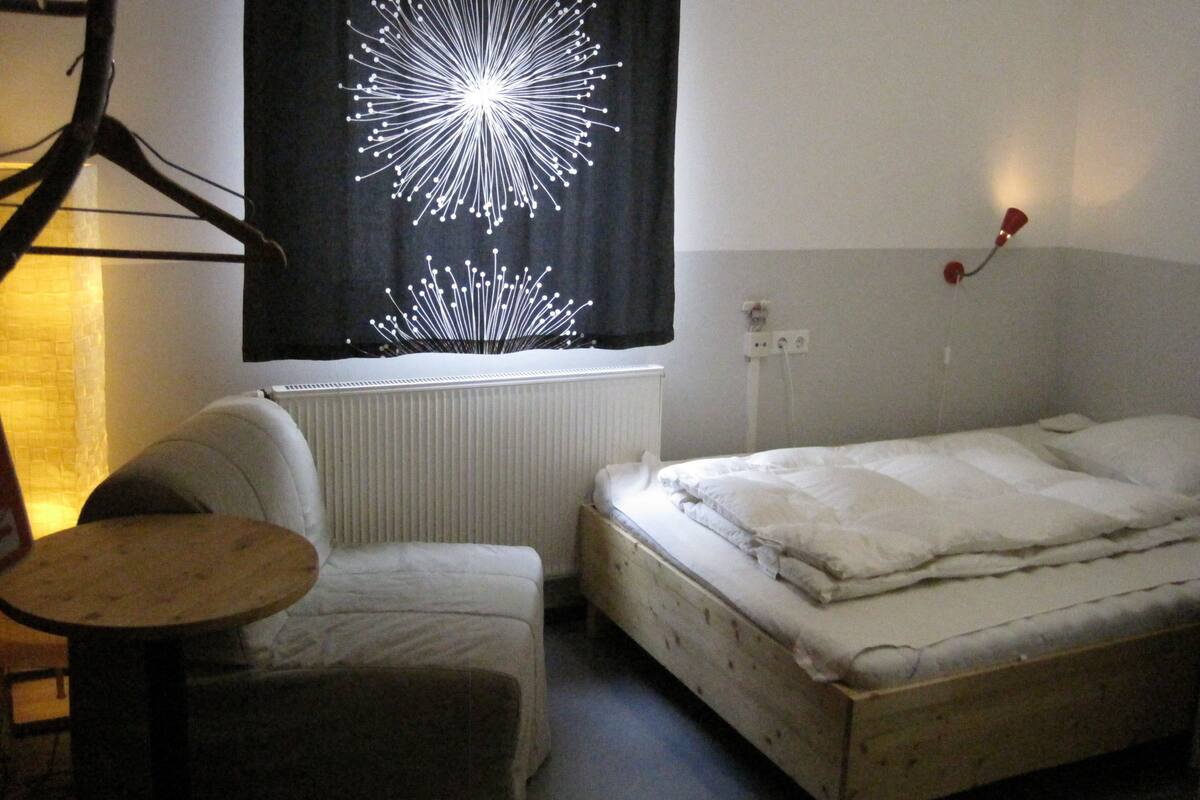 Une petite pièce simple, avec un lit, une chaise et une table.