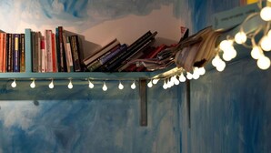 A bookshelf with books and a string of lights. - Babelfish Hostel (Würzburg)