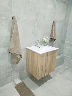A bathroom with a wooden cabinet, a white sink, and two towels hanging on the wall. - Shawu Lodge & Conference (Bloemfontein)