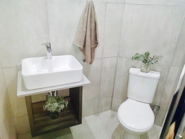 A bathroom with a white sink, a toilet, and a towel hanging on the wall.