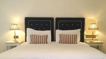 A double bed with a dark headboard, two bedside tables with lamps, and striped pillows.